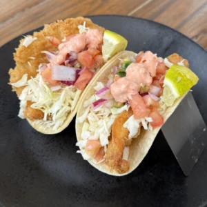 Fish tacos with cabbage, pico de gallo, house sauce, and lime wedges served at The Coffee Garden in the Heights, Houston TX 77007.